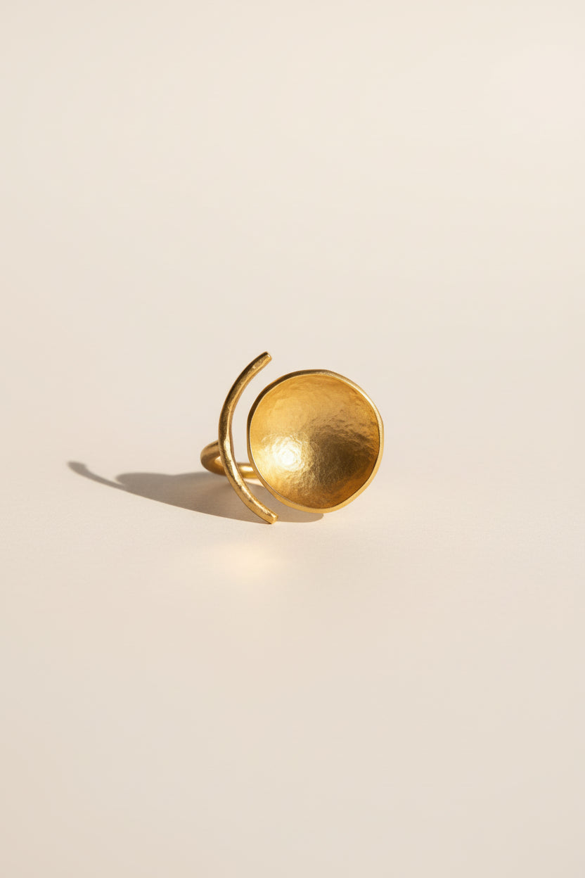 Gold sculptural bowl statement ring photographed alone, light beige background