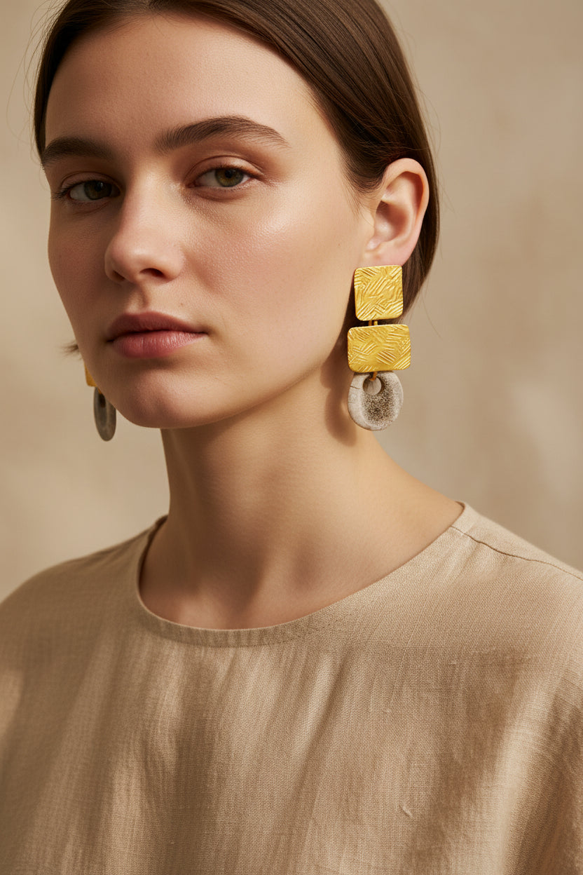Model wearing gold square deer horn drop earrings with beige linen top, relaxed pose