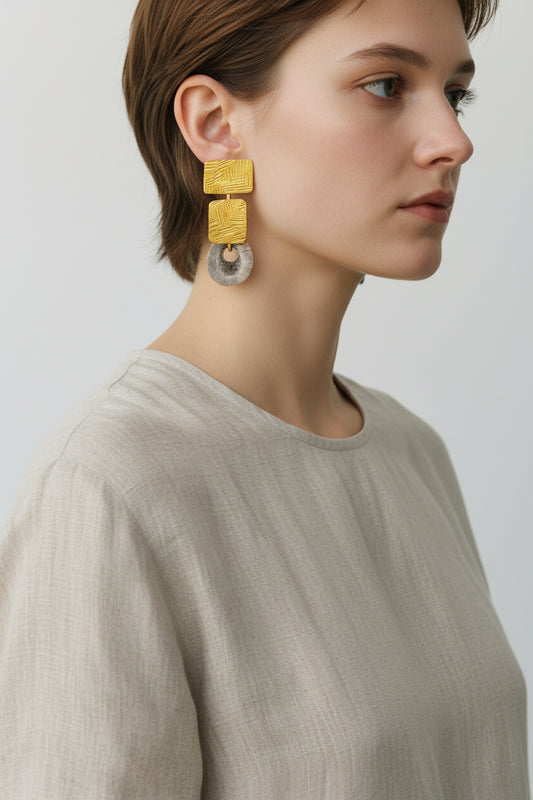 Model wearing gold square deer horn drop earrings with linen top, front view