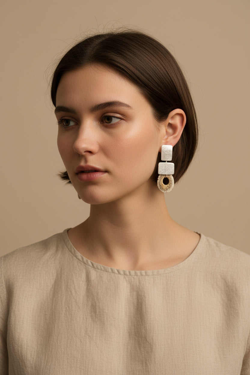 Model wearing gold square deer horn drop earrings with beige linen top, soft daylight portrait