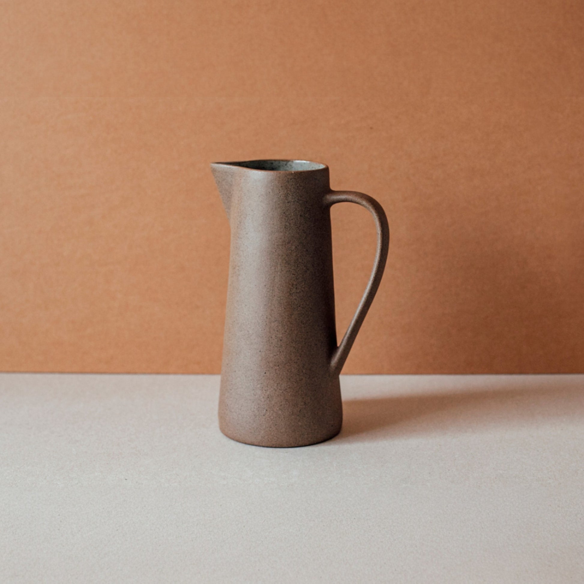 Handmade terracotta ceramic pitcher with glazed interior and sculptural handle