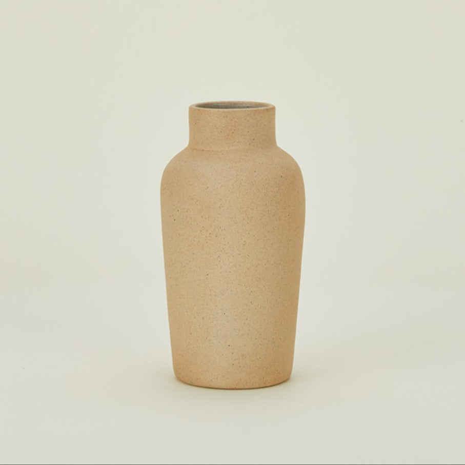 Handmade sand terracotta bottle vase on a soft, neutral backdrop.
