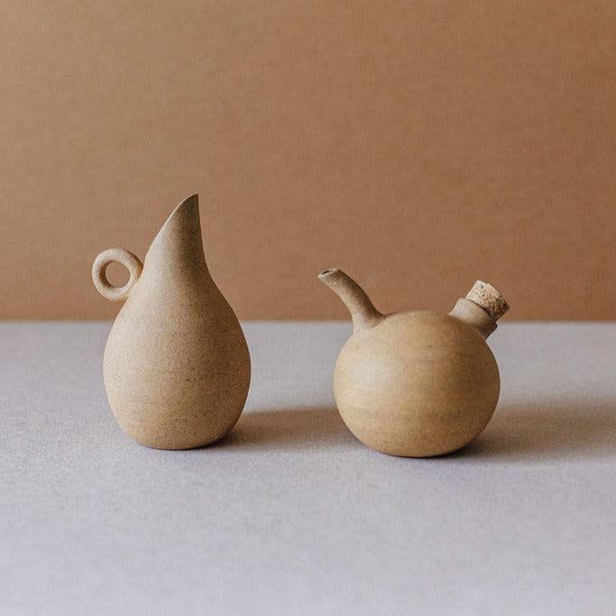 Natural sand-toned ceramic oil and vinegar cruet set, handmade in high-temperature clay, standing upright on a neutral background