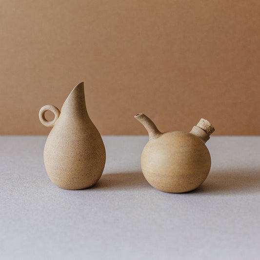 Natural sand-toned ceramic oil and vinegar cruet set, handmade in high-temperature clay, standing upright on a neutral background