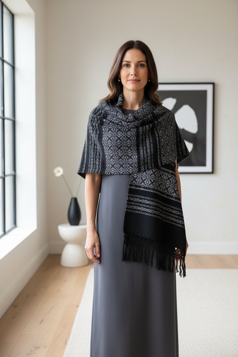 Handwoven cotton rebozo shawl in charcoal and black draped over shoulders, showcasing fringe and woven details.