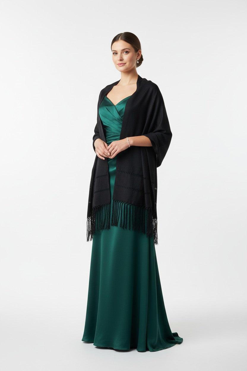 Elegant woman in a black handwoven shawl over an emerald green satin evening gown, posing against a clean studio background.