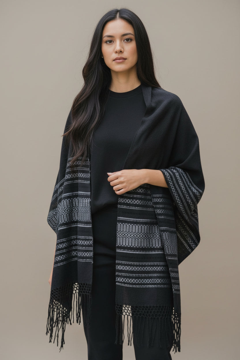 Black handwoven cotton shawl worn as a wrap, showing woven border details and fringe