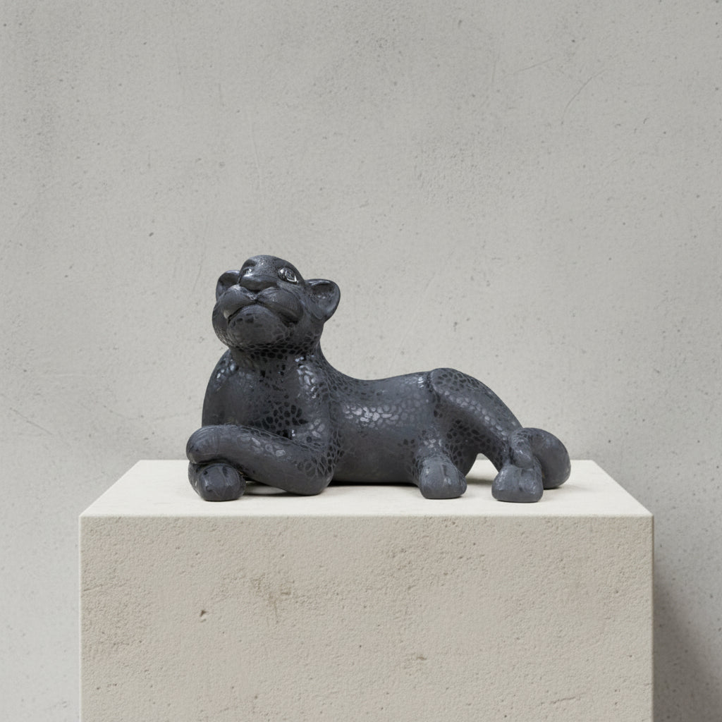 Black hand-painted clay jaguar figurine handmade in Amatenango del Valle, Chiapas, resting on a white pedestal with a gray background