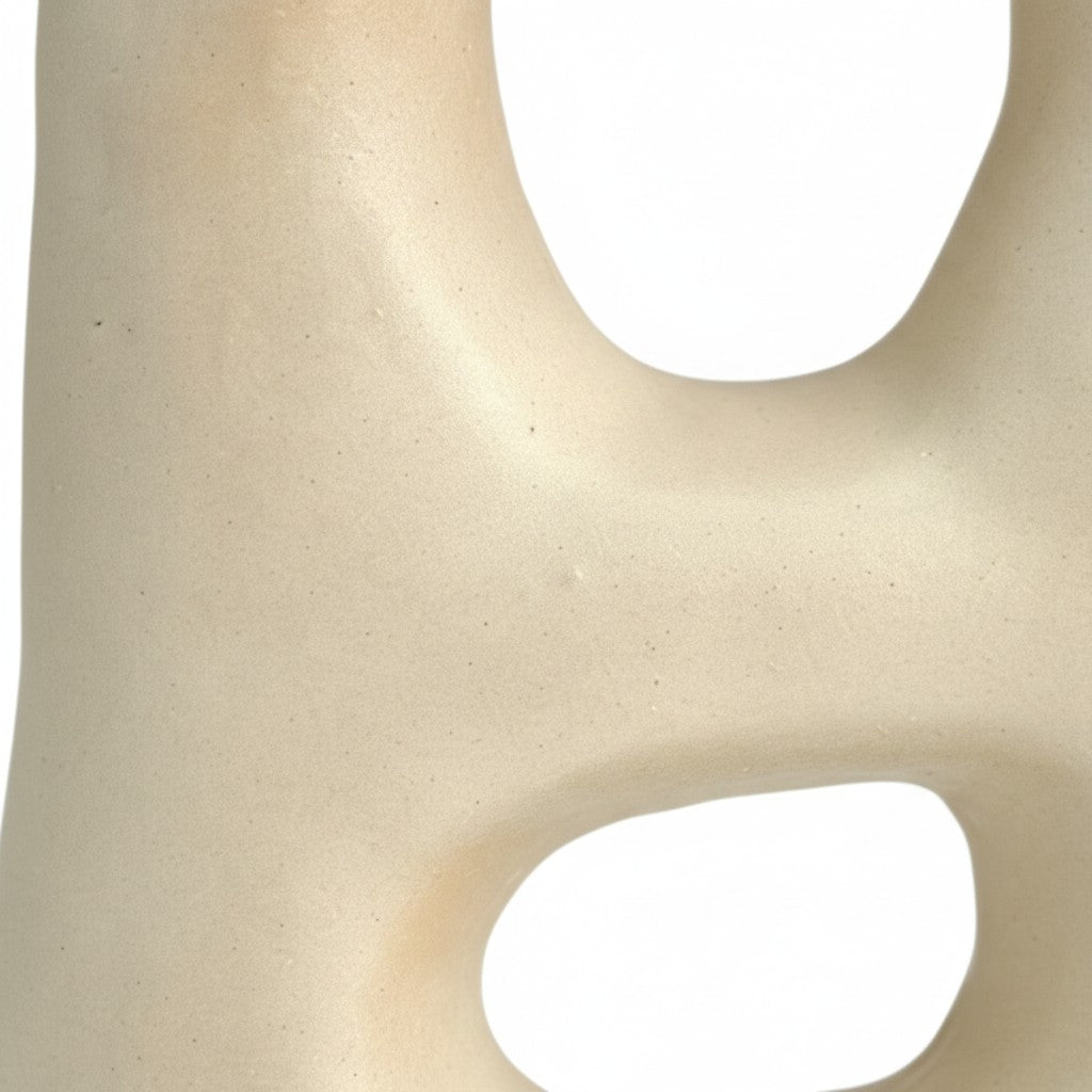 Close-up of off-white sculptural vase showing smooth texture and geometric cutouts.