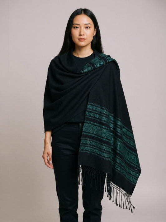 Woman wearing a black handwoven cotton rebozo shawl with woven borders and fringe on a neutral background