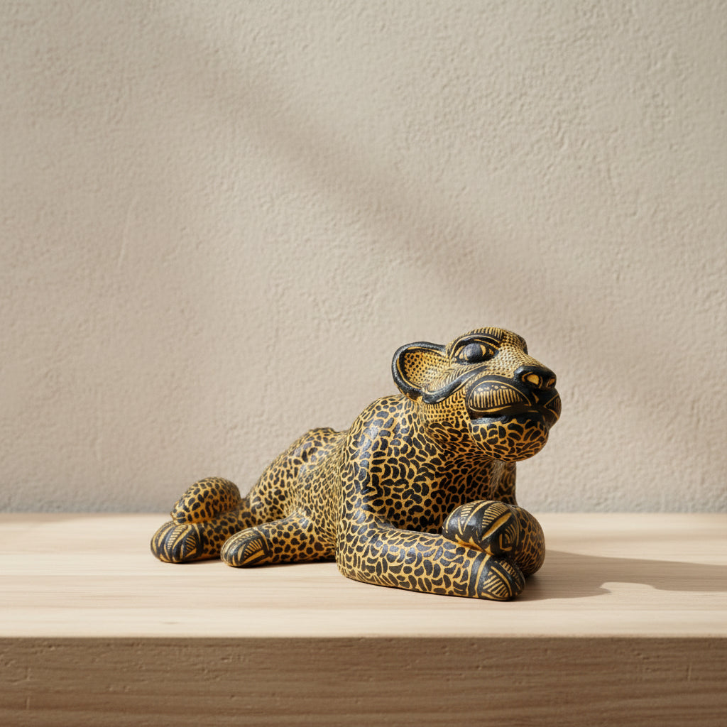 Hand-painted clay jaguar sculpture with traditional spotted pattern on a wooden surface