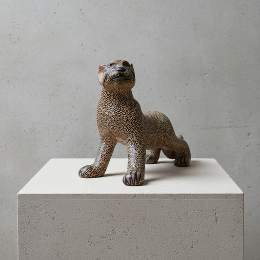 Hand-painted Mayan clay jaguar sculpture displayed on a white stone pedestal against a textured gray wall