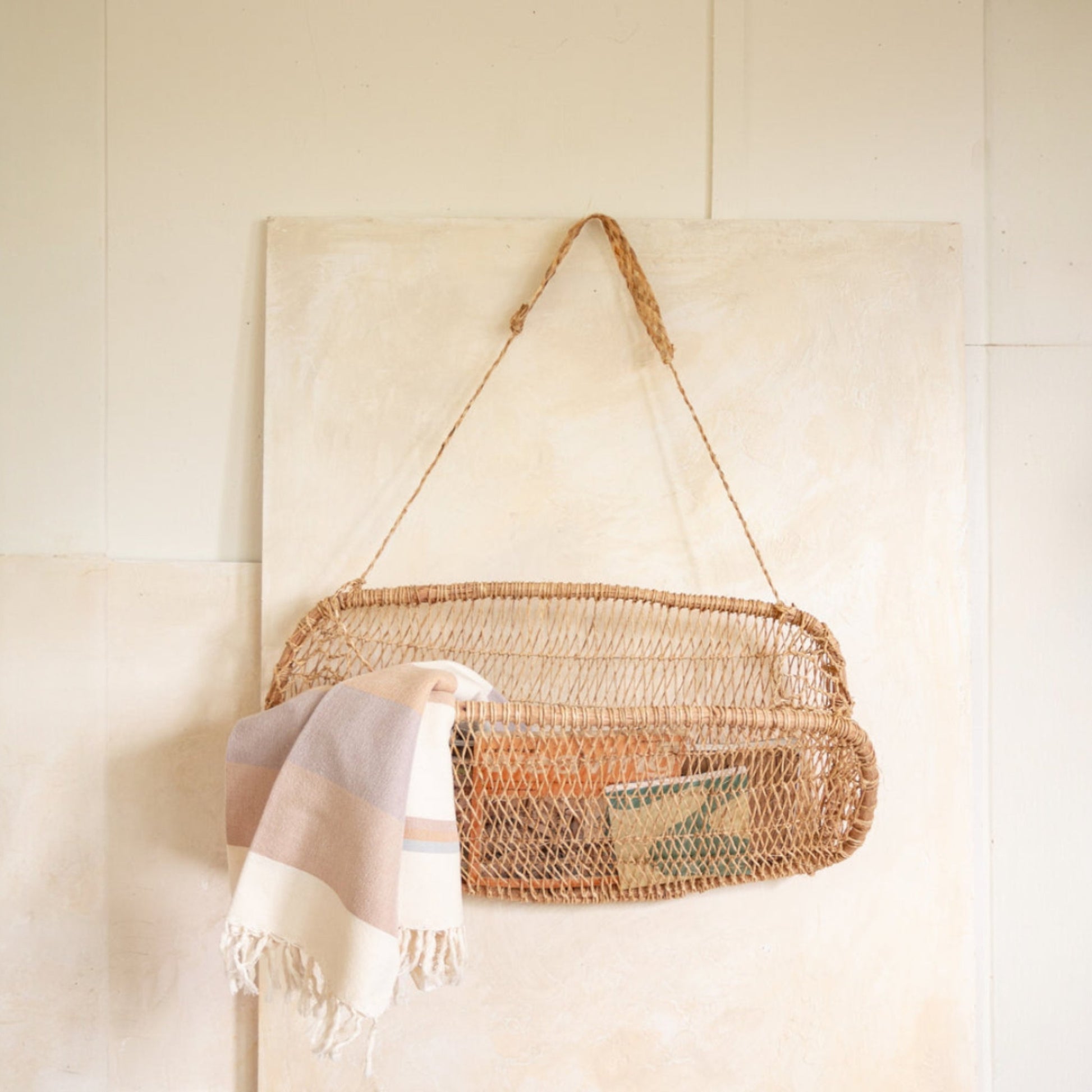 Jonote wall-mounted basket displayed with a striped towel and books against a tiled wall.